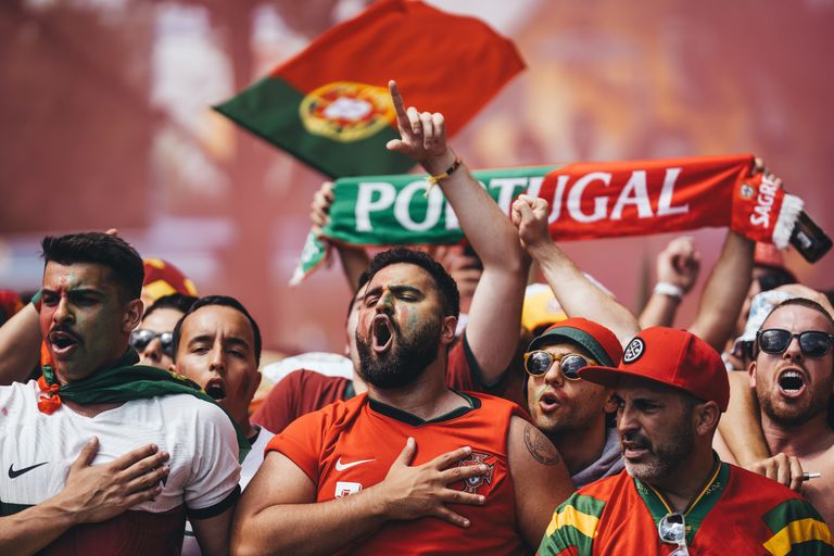 Passionate Portugal football supporters cheering with flags and scarves in vibrant celebration.